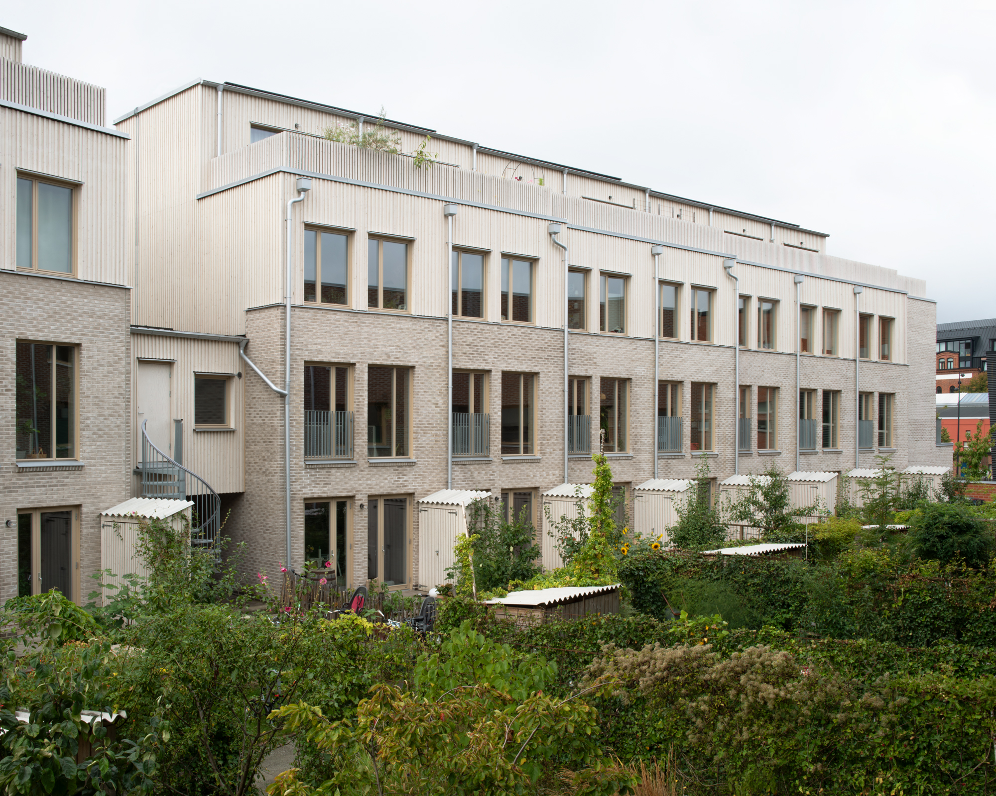 BRF Trädgårdshusets gård med tegel- och trähus och gröna odlingslotter